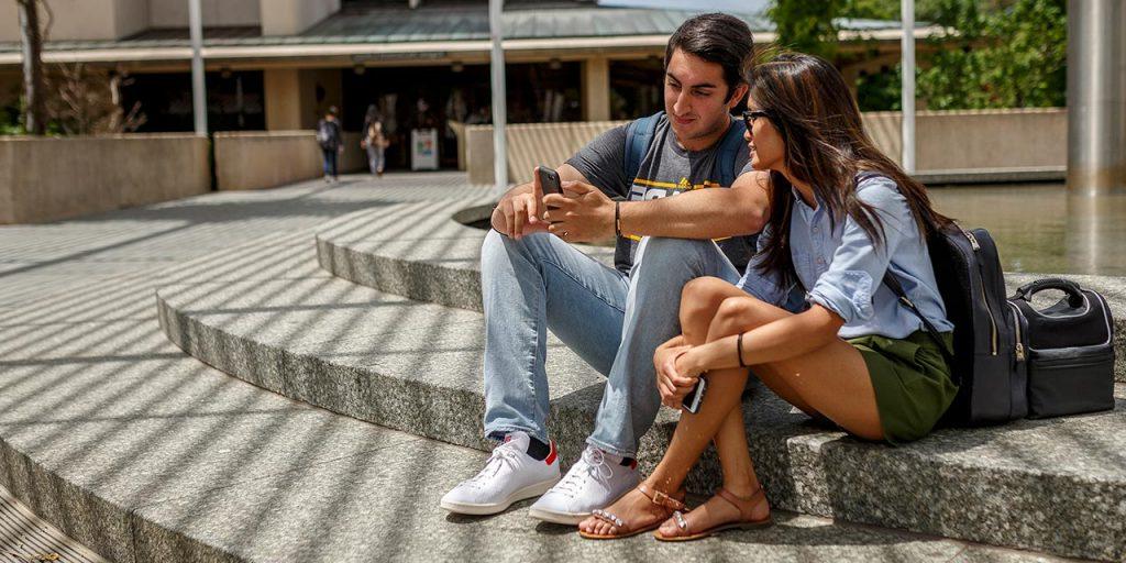 students on campus looking at a phone